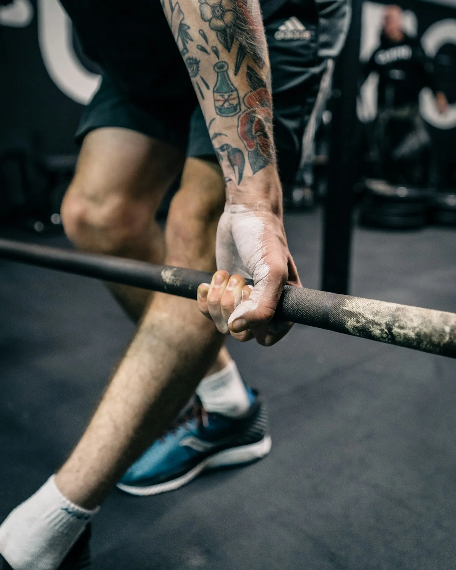 Chalked hands gripping a knurled barbell